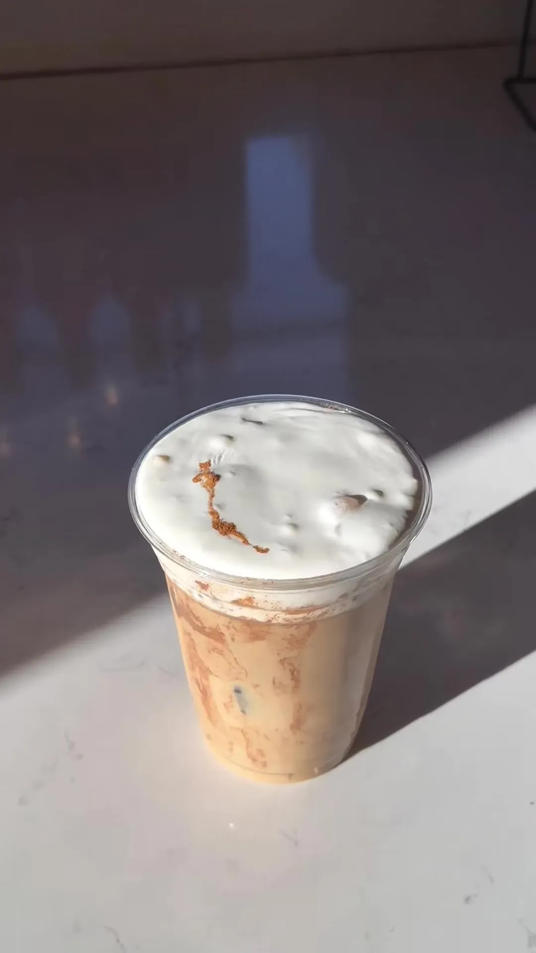 Iced drink topped with salted maple cold foam and caramel