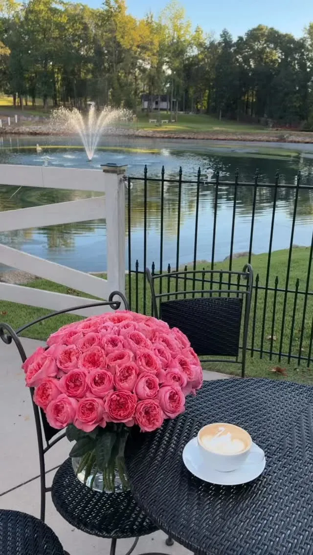Pink roses and a latte on a patio table overlooking the pond fountain