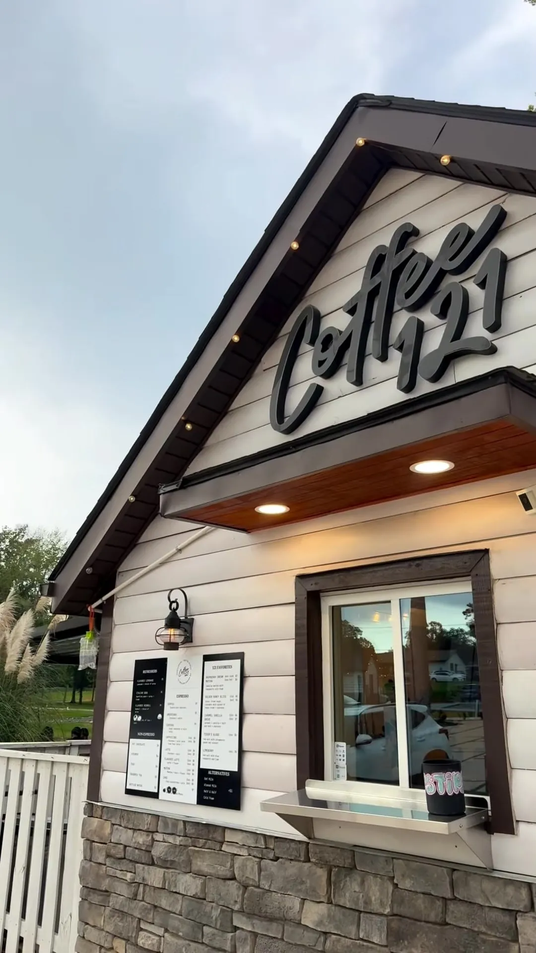 The white 121 Coffee building with its Coffee 121 sign, menu boards and stone base